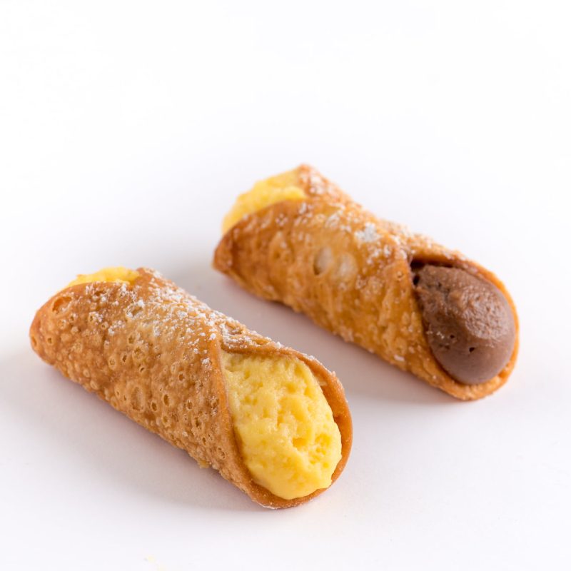 Two mini Sicilian cannoli filled with custard and chocolate cream